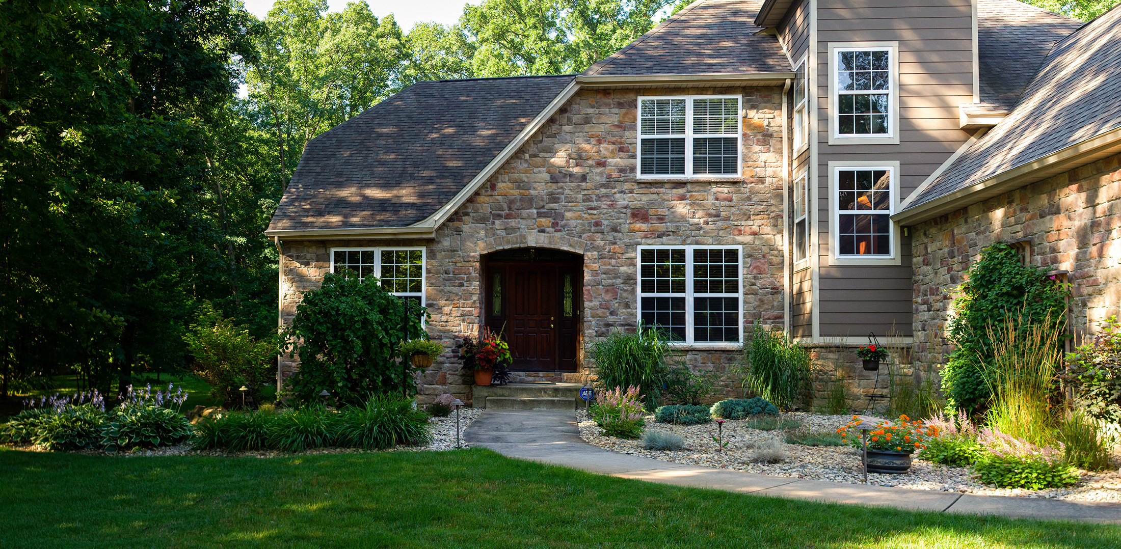 Front of a stone house with walkway and landscaping